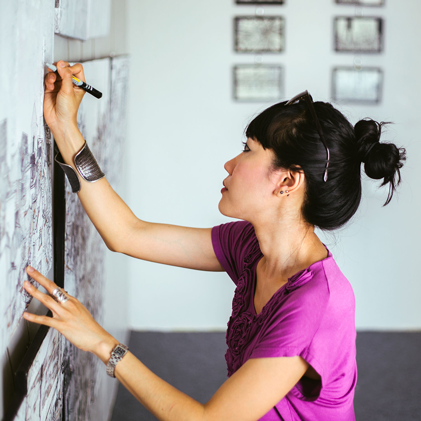 Woman sketching on large pieces of paper attached to the wall